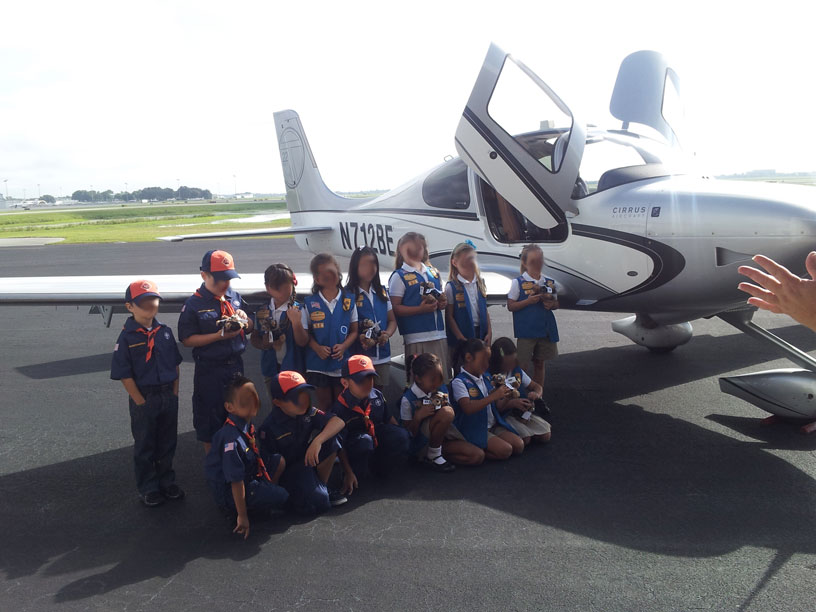 Image of Girl Scouts and Boy Scouts group in front of Cirrus airplane