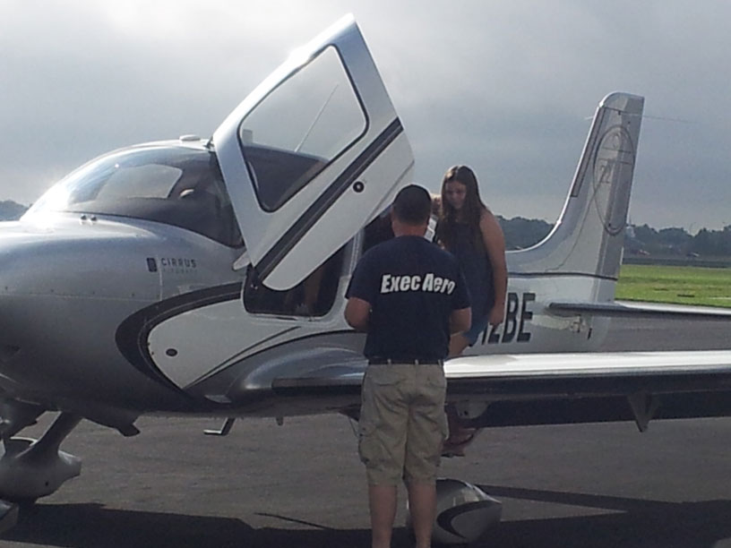 Image of Exec Aero employee showing a Cirrus airplane to a Girl Scout