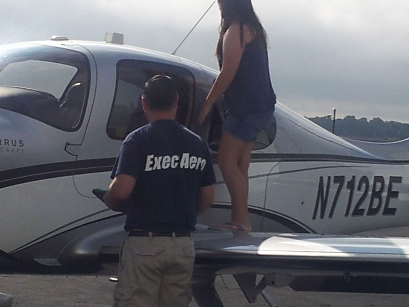 Image of Exec Aero employee showing a Cirrus airplane to a Girl Scout