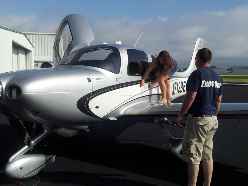 Image of Exec Aero employee showing a Cirrus airplane to a Girl Scout