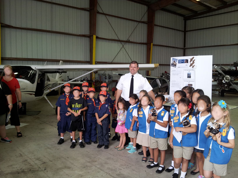 Image of Boy and Girl scouts posing with pilot for pictures