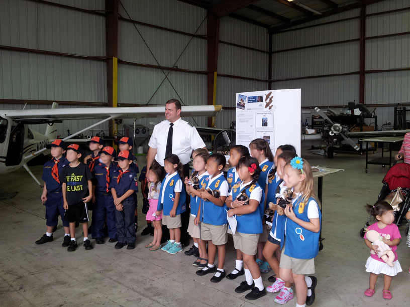 Image of Boy and Girl scouts posing with pilot for pictures